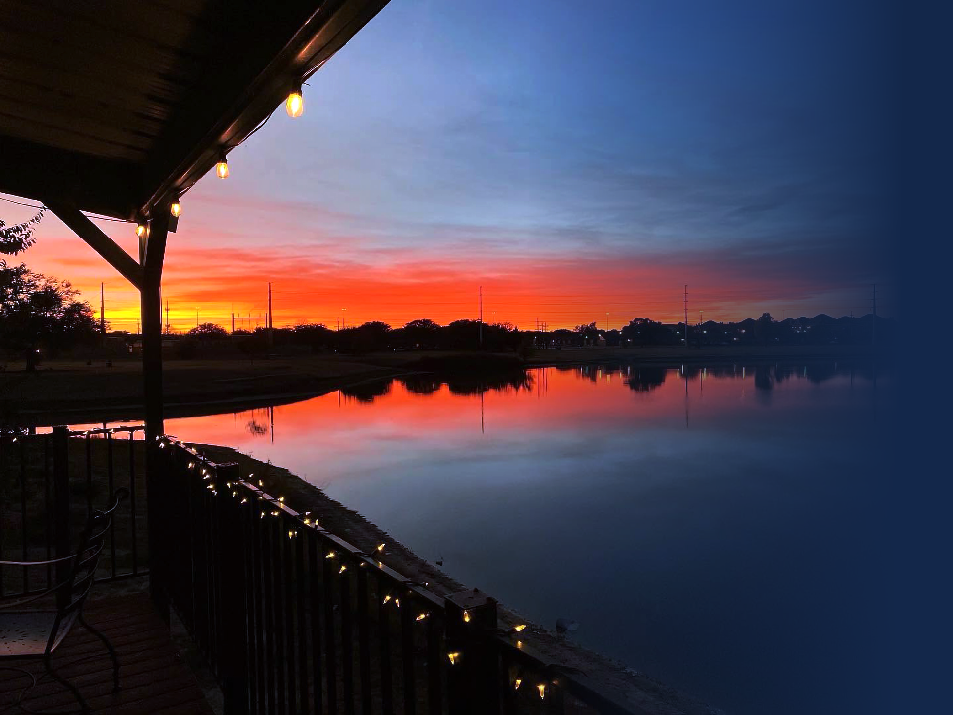 Sunset over the playa lake from The Gas Light's deck, string lights glowing along the rail